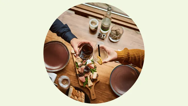 Two people raise a glass over a board of local food