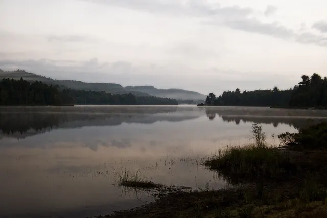 Forest-ringed lake and hills in the early-morning mist