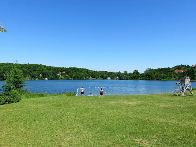 Grassy municipal beach and supervised swimming area on Lac Carré in the Laurentians