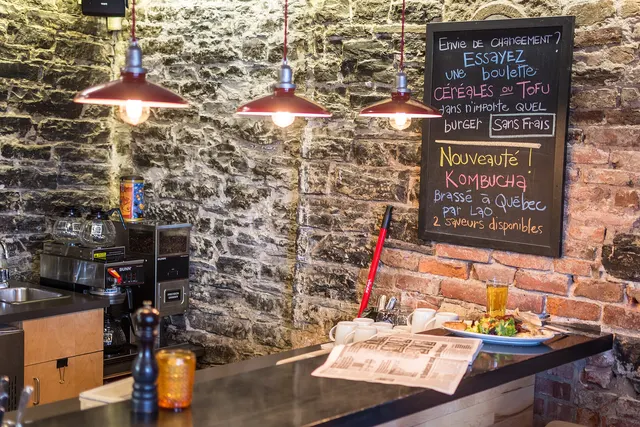 Restaurant with bare stone walls, a chalkboard menu and hanging lamps in Old Quebec