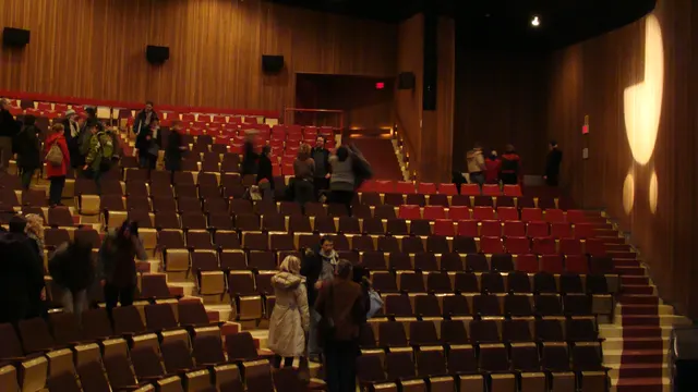 Performance hall with rows of red seats and wood-panelled walls