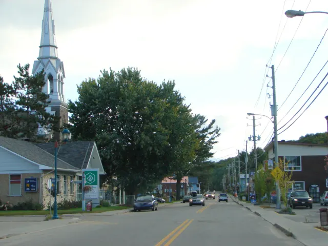 Chénéville's main street with shops, cars and the church steeple