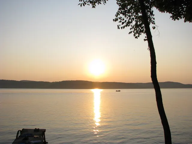 Sunset over Lac Gagnon, with a silhouetted tree and a small boat in the distance
