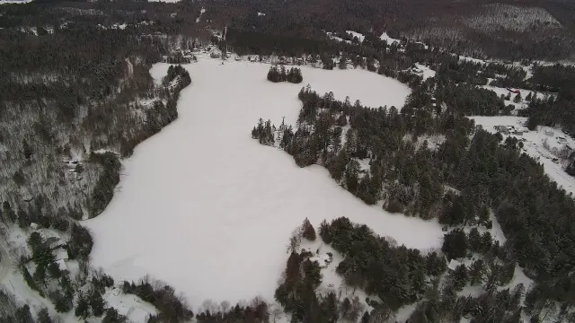 Aerial view of frozen, snow-covered Lac Lévesque surrounded by forest in January