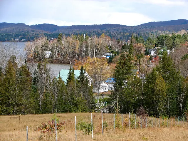The village of Lac-des-Plages on the lakeshore, with coloured trees and mountains