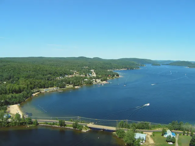 Aerial view of Lac Simon with its beach, wooded shores and a boat