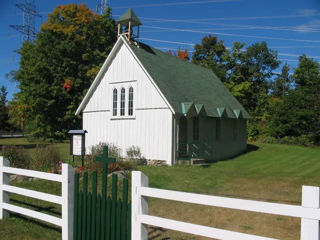 The small white wooden St. Thomas Anglican Church behind a white fence in Silver Creek