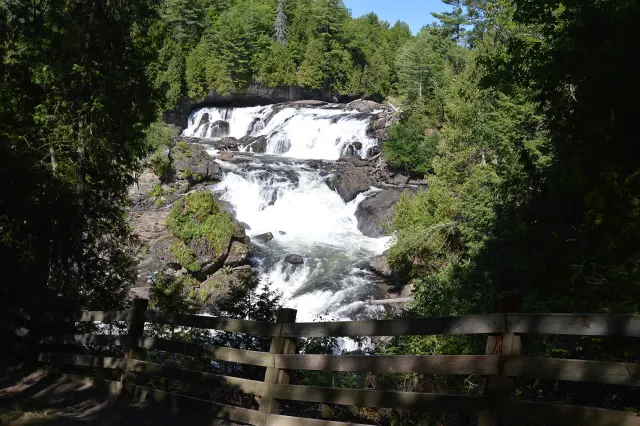 The Plaisance falls seen from a fenced lookout, between conifers
