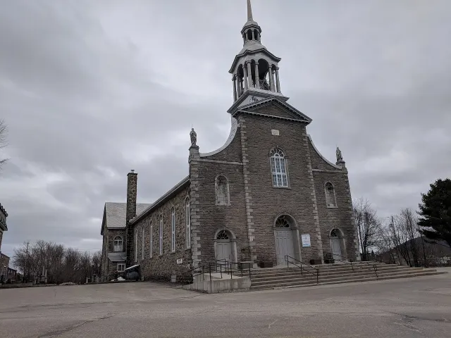 Église en pierre grise de Saint-André-Avellin sous un ciel couvert