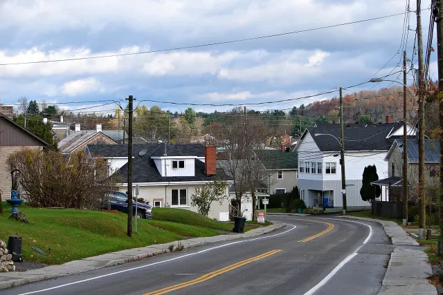 A curving street in Saint-André-Avellin, houses and autumn hills