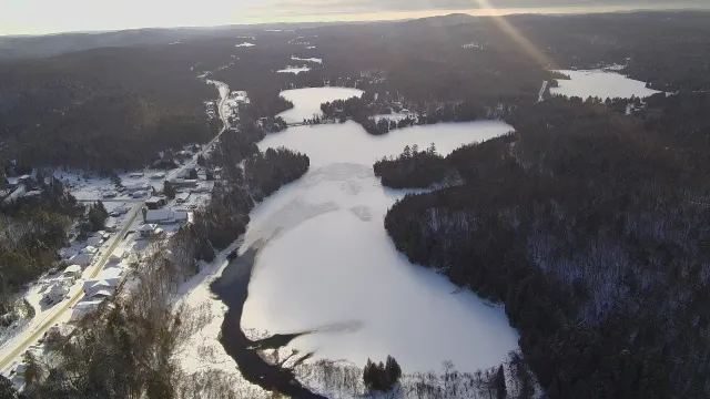 Aerial view of frozen Lac Saint-Émile and the village under snow in December